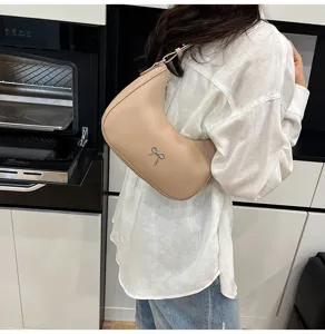 Model met een beige zadeltas met zilveren strikdetail in een moderne keuken