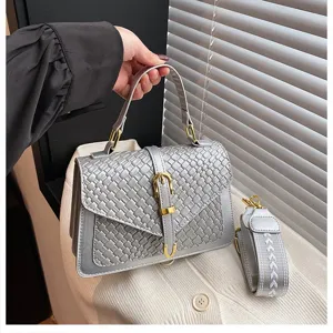 Vista detallada de un bolso bandolera gris tejido con una elegante hebilla dorada chic