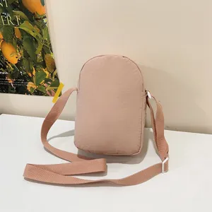 Vista trasera del bolso bandolera de nailon rosa para móvil sobre fondo minimalista