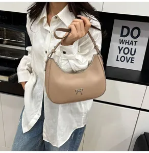 Gedetailleerd overzicht van een stijlvolle beige hobo-tas met een zilveren strik.