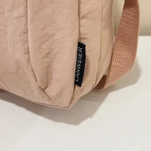 Primer plano de la textura de nailon impermeable y la etiqueta de un bolso rosa.