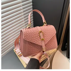 Primer plano de bolso rosa con textura trenzada, herrajes dorados y correa estampada