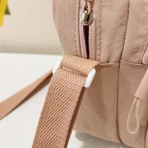 Detalle de cerca que muestra la correa y la cremallera de un bolso bandolera rosa
