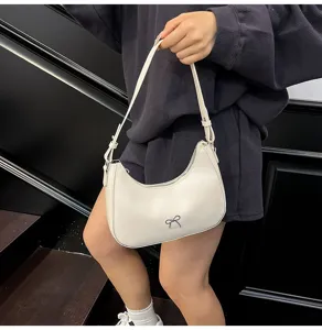 Chique gebroken witte kunstlederen zadeltas met strikdetail gedragen door model