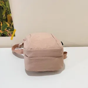 Vista detallada de un bolso bandolera de nailon rosa impermeable con correa ajustable.