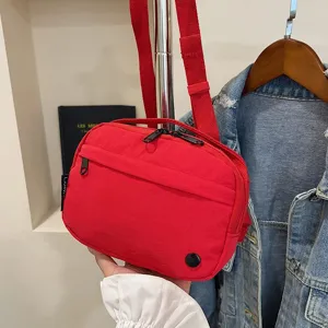 Primer plano de una riñonera roja de tela Oxford con dos compartimentos de cremallera.