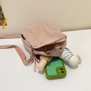 Vista detallada de un bolso bandolera de nailon rosa con espacio para teléfono y cosméticos