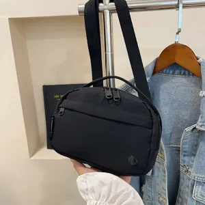 Primer plano de un bolso bandolera negro de tela Oxford impermeable en la mano