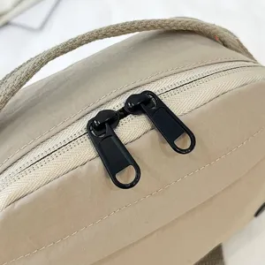 Primer plano detallado de las cremalleras dobles negras en un bolso de tela oxford caqui