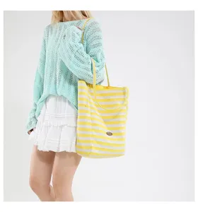 Bolso tote de lona a rayas amarillas y blancas en modelo en un entorno de estilo casual