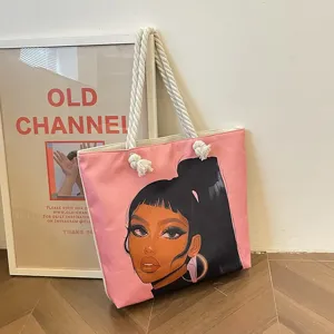 Vista detallada del bolso tote rosa con una ilustración estilizada de una niña negra.