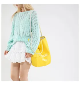 Detalle de un bolso tote de lona amarillo brillante con un elegante texto en cursiva.