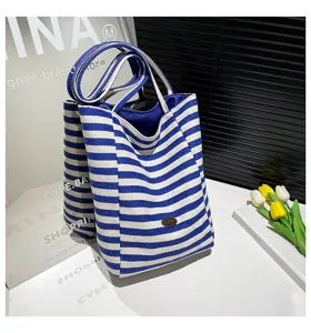 Vista detallada de un bolso tote de lona con rayas azules y blancas en un entorno casual