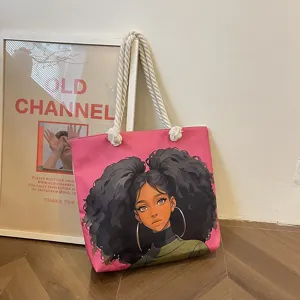 Primer plano de un bolso tote rosa con estampado de chica negra y asas de cuerda gruesa