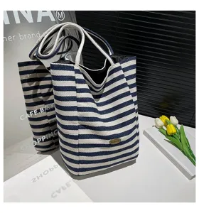Primer plano de un bolso tote de lona a rayas azules y blancas con placa Handmade.