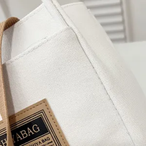 Detailed macro view of white canvas tote bag texture with brand label and brown strap