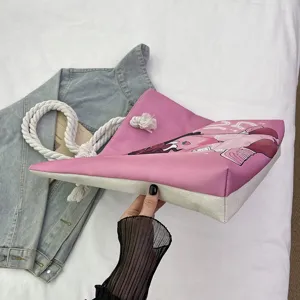 Vista detallada del bolso tote de lona rosa con estampado de chica negra y asas de cuerda