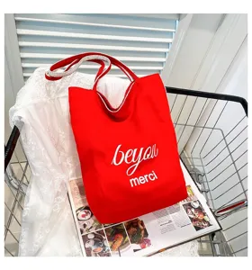 Bolso tote de lona roja con estampado 'be you merci' en un carrito de compras estilo