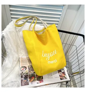 Primer plano de un bolso tote de lona amarilla con asas de rayas en un carrito de compra