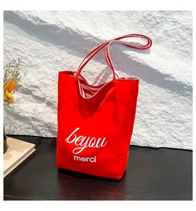 Bolso tote de lona roja vibrante con letras blancas y detalles de forro a rayas.