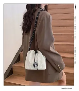 Dettaglio di una borsa a secchiello in nylon crema leggera su un outfit casual