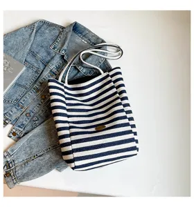 Bolso tote de lona a rayas azul marino con chaqueta vaquera sobre fondo blanco