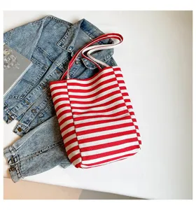 Bolso de lona a rayas rojas y blancas presentado sobre una elegante chaqueta vaquera