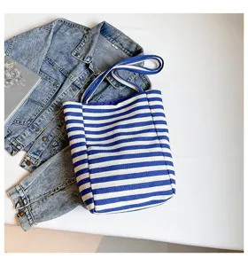 Detalle de un bolso tote de lona a rayas azules y blancas en un entorno casual de flat lay