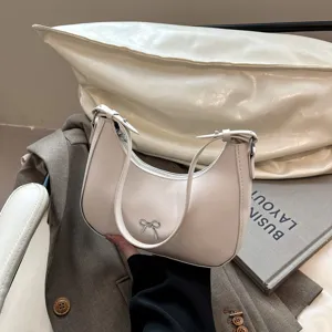 Detailopname van een crèmewitte hobo-tas met een verfijnd zilverkleurig strikje ornament
