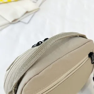 Vista detallada de un bolso de tela Oxford beige impermeable con cremalleras negras robustas