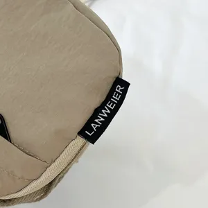 Detalle de la etiqueta tejida LANWEIER en una riñonera de tela Oxford color canela