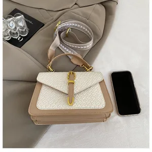 Bolso de mano beige estructurado con textura tejida y correa sobre fondo de blazer