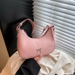 Elegante roze onderarm zadeltas met een stijlvol zilveren strikdetail in de hand
