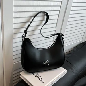 Elegante zwarte hobo-tas met een zilveren strikdetail in een lifestyle-omgeving.