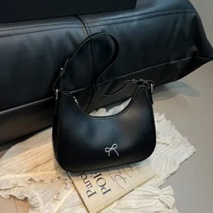 Detailopname van een zwarte hobo-tas met een prachtig elegant zilveren strikje.