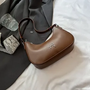 Gedetailleerd overzicht van de bruine hobo-tas met een zilveren strik en een ritssluiting.