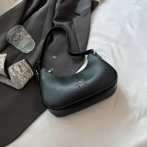 Stijlvolle zwarte okselzadeltas met zilveren strikdetail in een lifestyle-setting