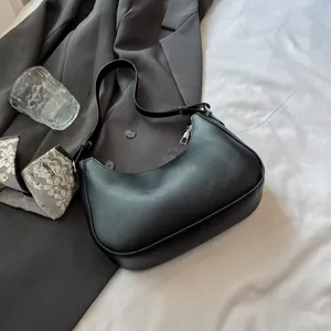 Detailweergave van een zwarte minimalistische hobotas op een grijze blazer en laken