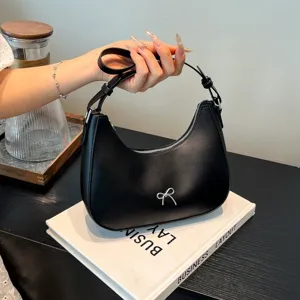 Elegante zwarte hobo schoudertas met een delicaat zilveren strikdetail en matte afwerking.