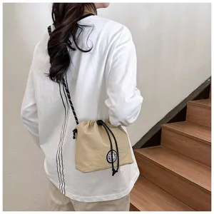 Dettaglio borsa a secchiello in nylon kaki con coulisse indossata casual