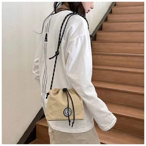 Borsa a tracolla casual in nylon beige con coulisse mostrata su una modella in posa.