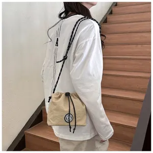 Borsa a coulisse in nylon beige indossata a tracolla da una modella in posa casual