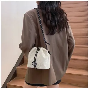 Modella che indossa una piccola borsa a secchiello in nylon con tracolla in corda