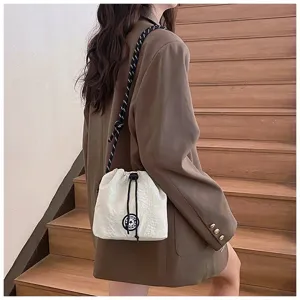 Vista dettagliata della borsa a secchiello in nylon bianco abbinata a un blazer marrone.
