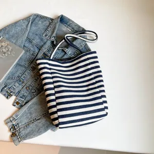 Bolso tote de lona a rayas azules y blancas con chaqueta vaquera sobre blanco