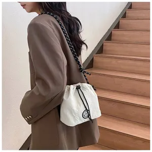 Dettaglio di una borsa a secchiello in nylon bianco con tracolla in corda su un modello.