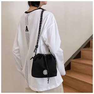 Dettaglio di una borsa a secchiello in nylon nero con coulisse e logo con stella.