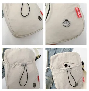 Detailweergaven van een beige nylon schoudertas met textuur, logo en vak voor mobiele telefoon.