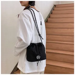 Vista dettagliata di una borsa a secchiello in nylon nero indossata a tracolla da una modella