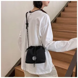 Modello che indossa una borsa a secchiello in nylon nero con coulisse e logo bianco